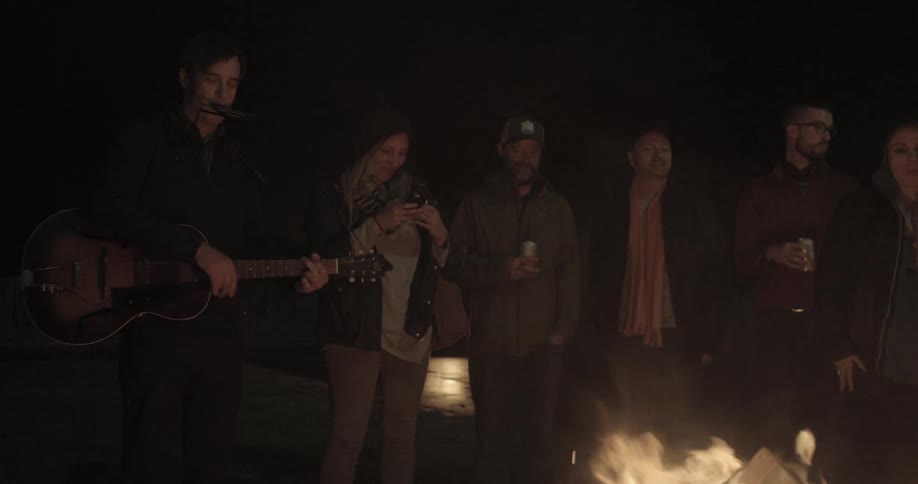 A group of people hangout by a camp fire
