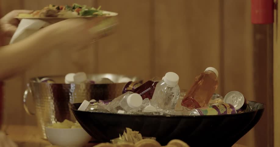 A person grabs a canned drink from an ice bucket