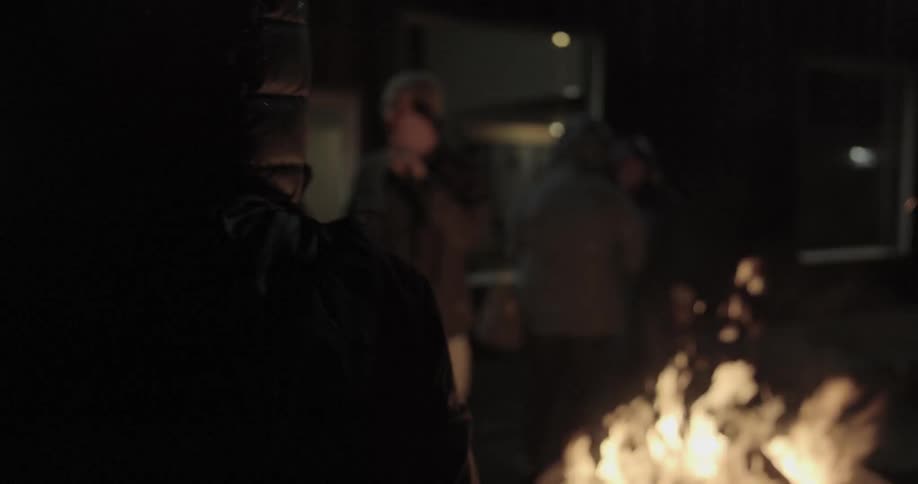A group of people standing around a bonfire while talking to one another