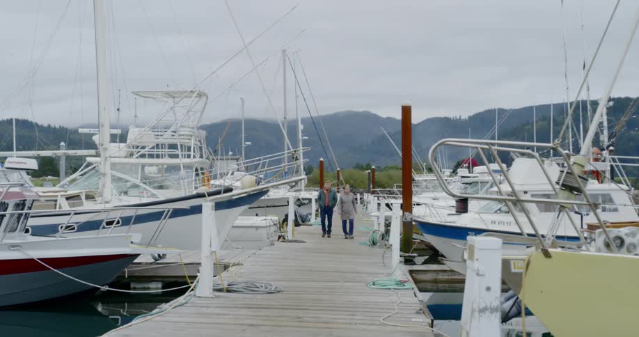 An older couple walk down a boat pier