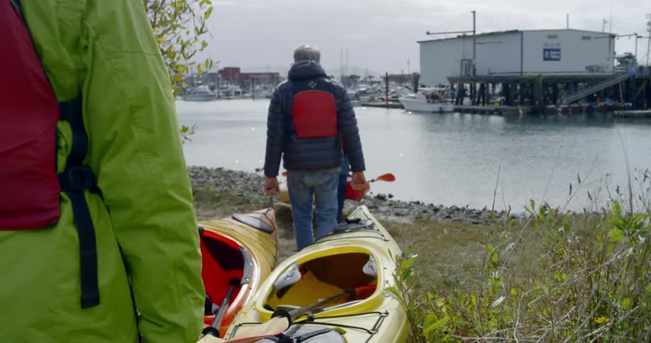 Men carry canoes toward the water