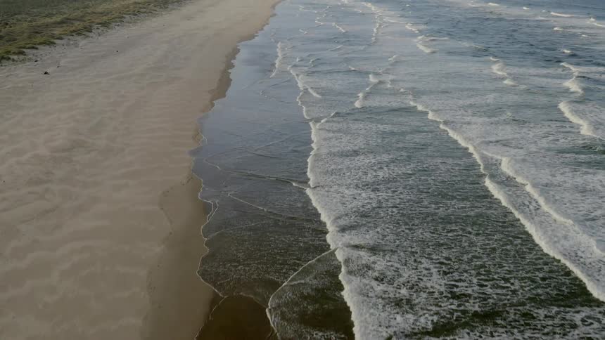 The waves slowly hit the beach on a foggy day