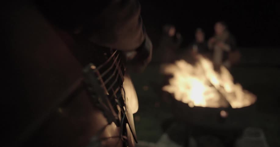 Man playing guitar in the bon fire