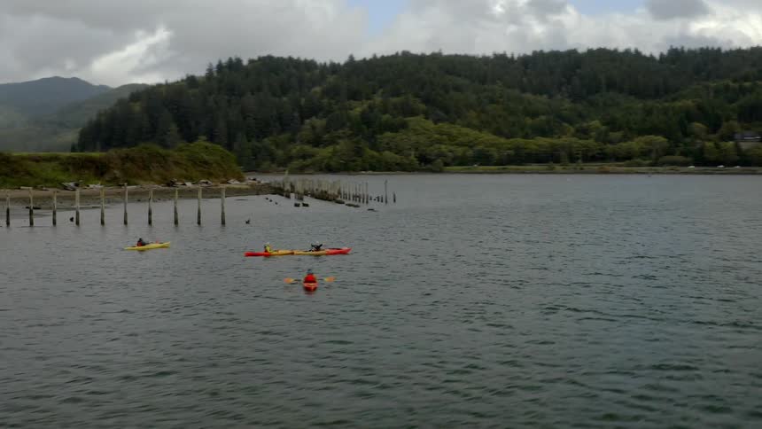 People are in kayaks in the water a bit off of the coast line