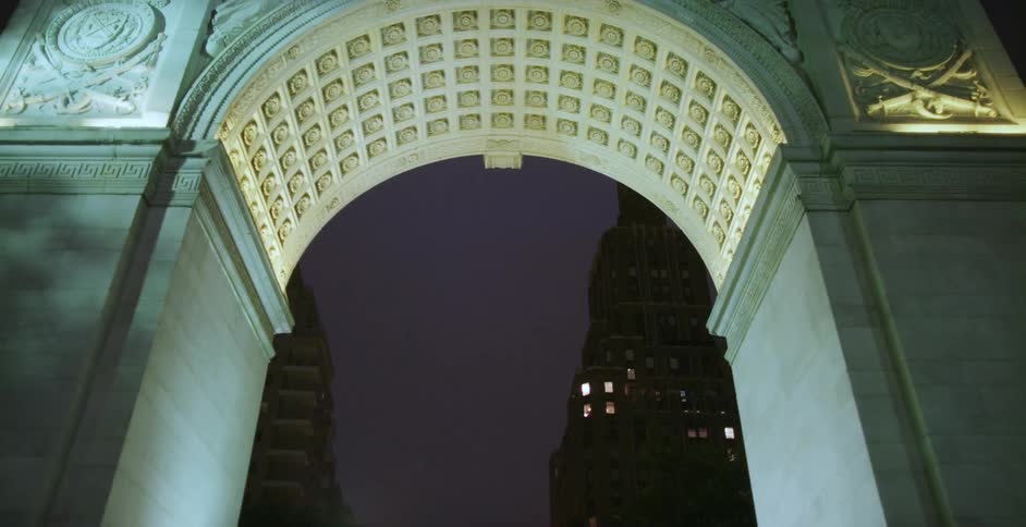 Traveling under the washington square arch in new york with the city lights behind it