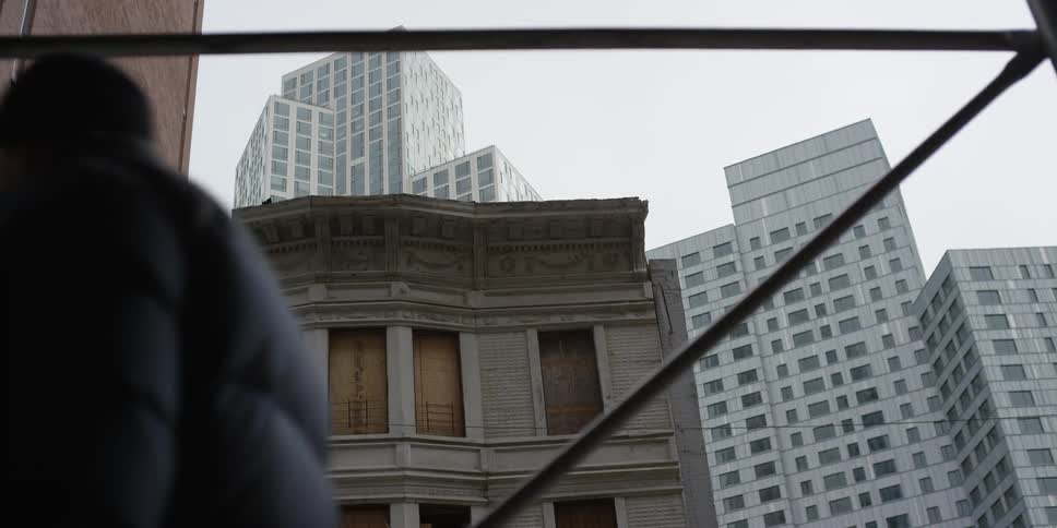 People walk by a city building with boarded up windows