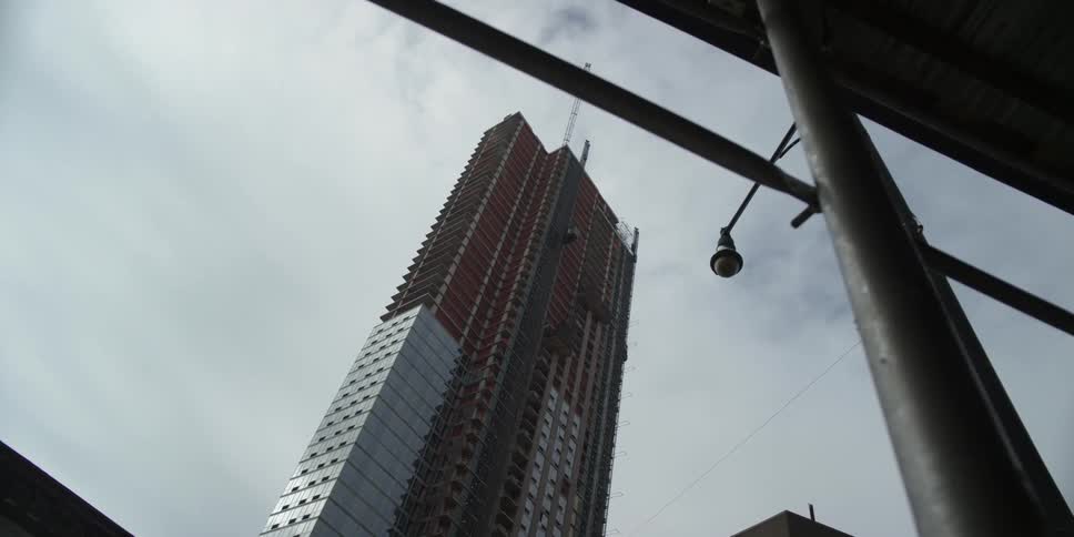 A view looking upward toward the top of a tall skyscraper on a cloudy day