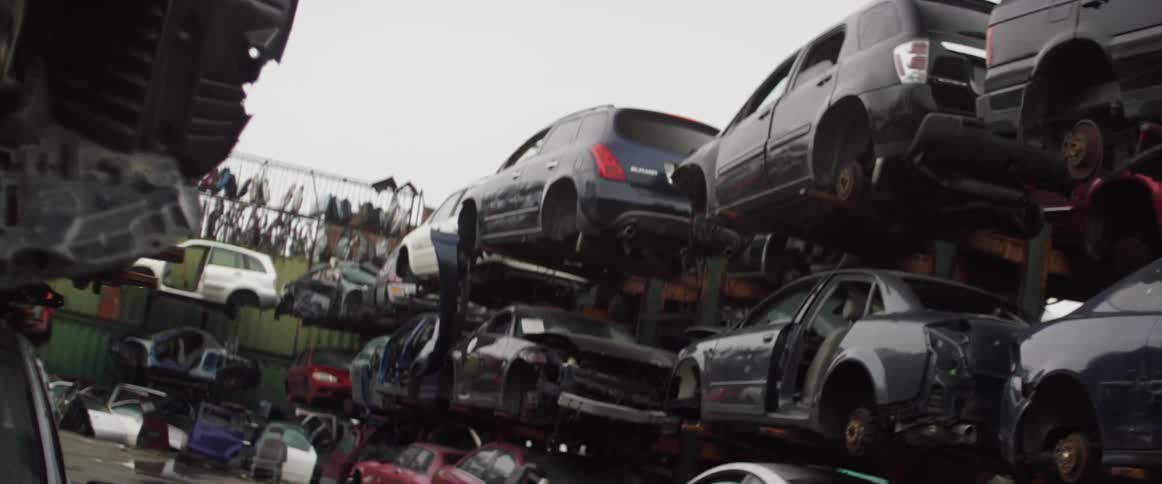 Cars are lined up and stacked in a junkyard