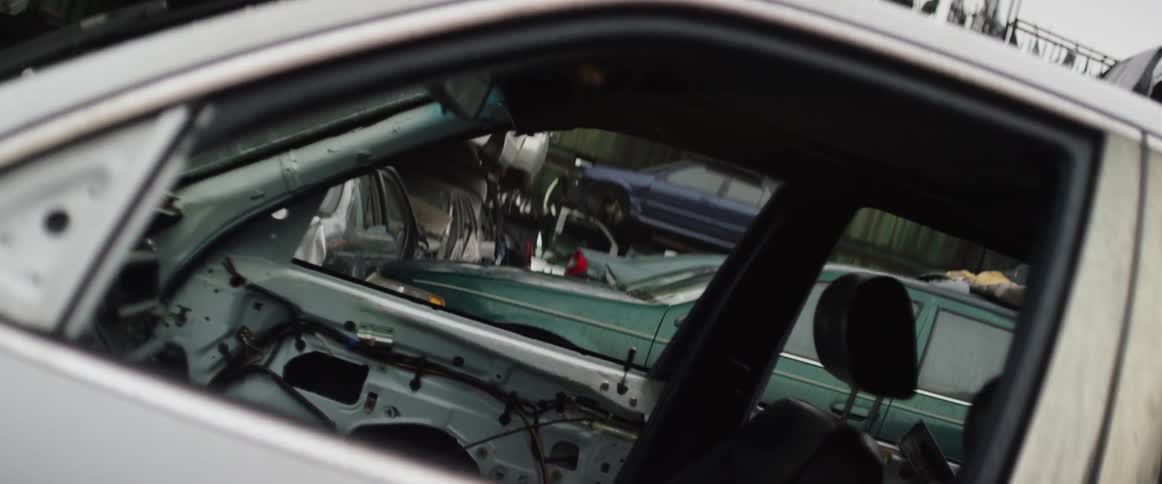 Cars sit in a junkyard