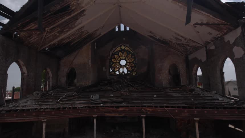 A burnt out, destroyed church with interior exposed as the camera zooms into the interior