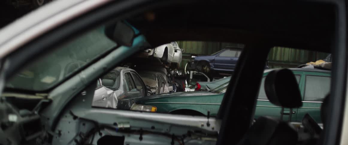 Stripped cars are stacked and lined up in a junkyard
