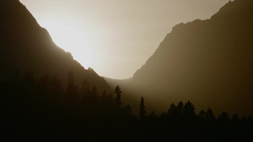 The sun sets behind the silhouetted mountains
