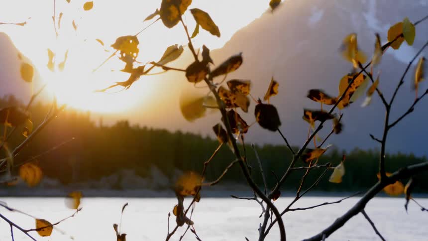 Sun goes down behind the snow capped mountains on a windy day
