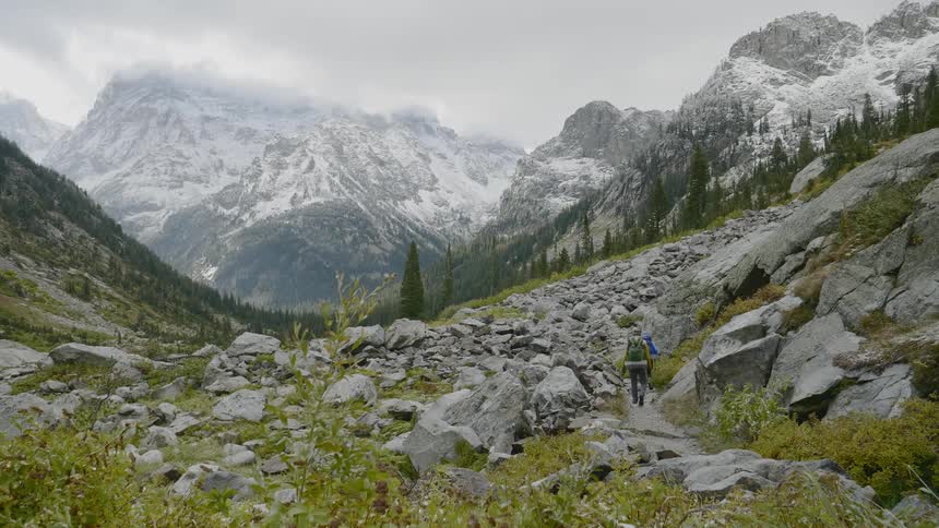 Two people hiking in a valley with mountains in the background