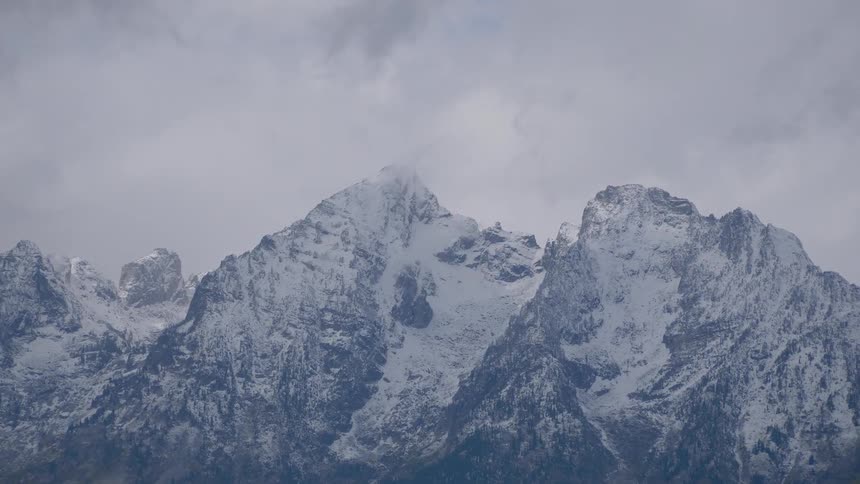 Clouds move over snowy mountains
