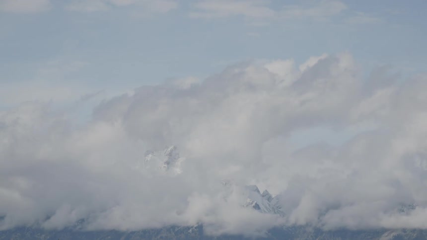 Timelapse of clouds forming over snowy mountain range