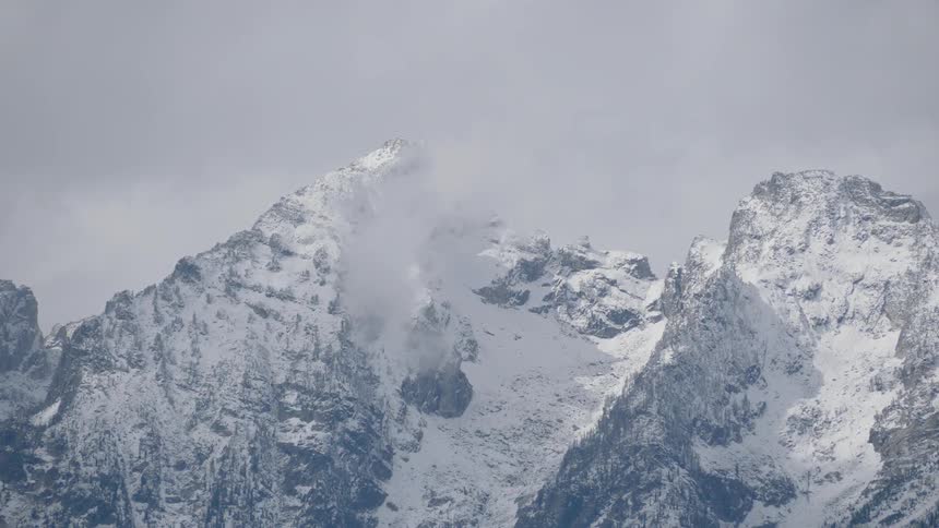 A snow covered mountain near the sky and clouds