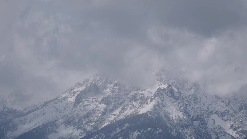 Clouds pass over the top of a mountain