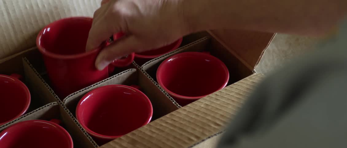 Person packing mugs into a box