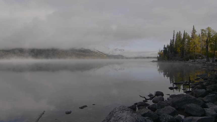 A lake with trees and the sky in the background