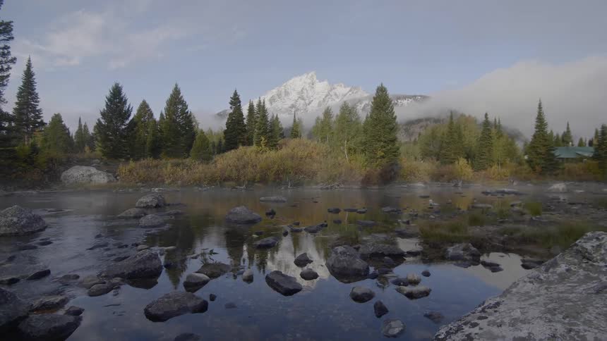 A scenery of a rocky lake and forest