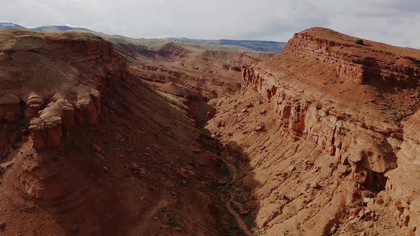 From high above the ground an enormous canyon filled with reddish brown dirt and rocks can be seen