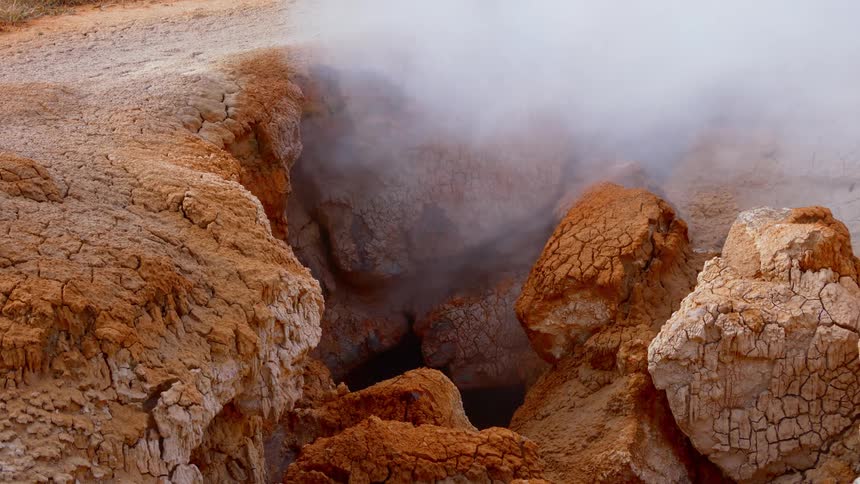 Steam rises from a rocky formation