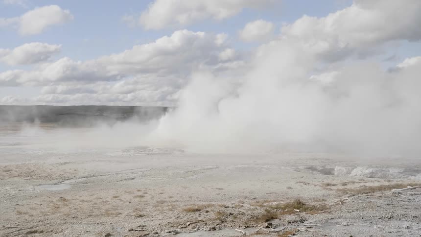 A geyser with water and steam with the sky in the background