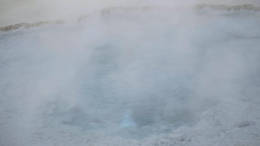 A bubbling natural outdoor hot spring shrouded in steam