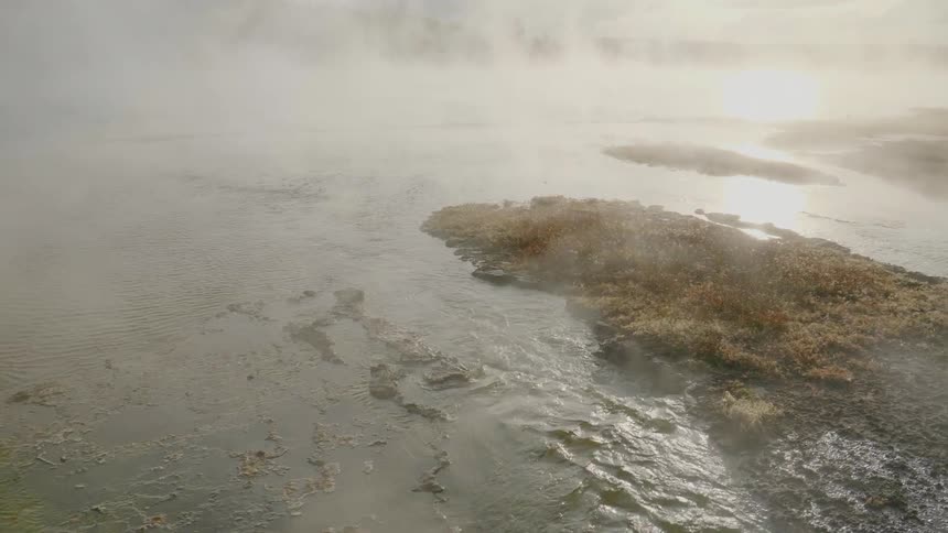 Mist and fog from a waterfall hangs over the flowing water