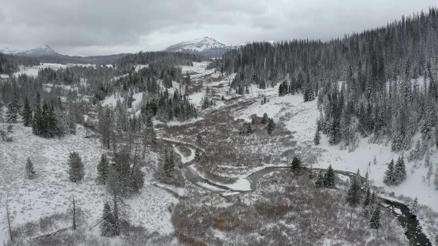 A frozen stream winding through a snowy mountain landscape