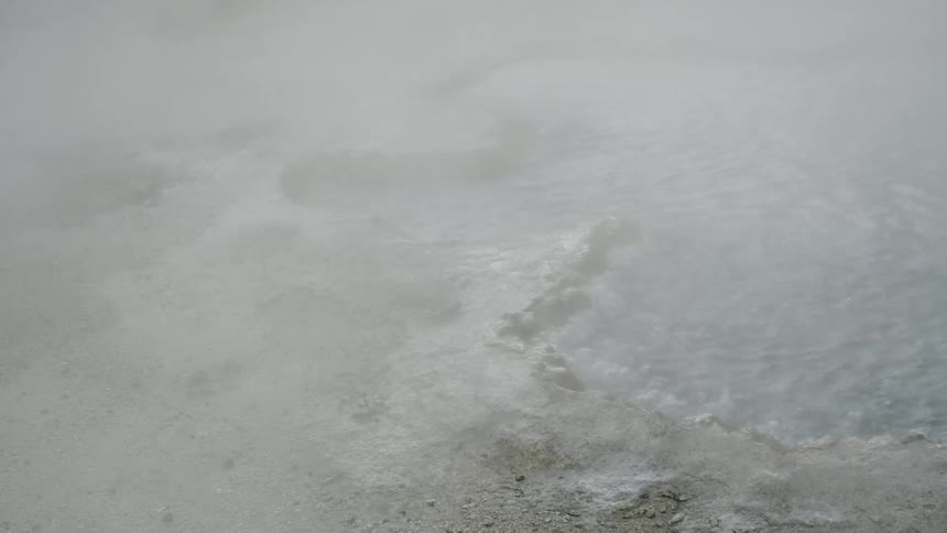 Steam rises from a bubbling hot spring in rock