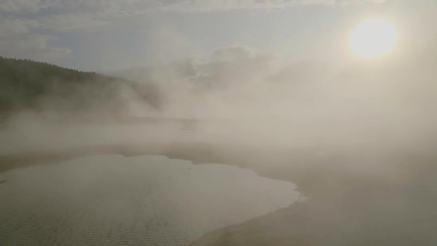 Mist crosses the water as the sun shines brightly in the sky