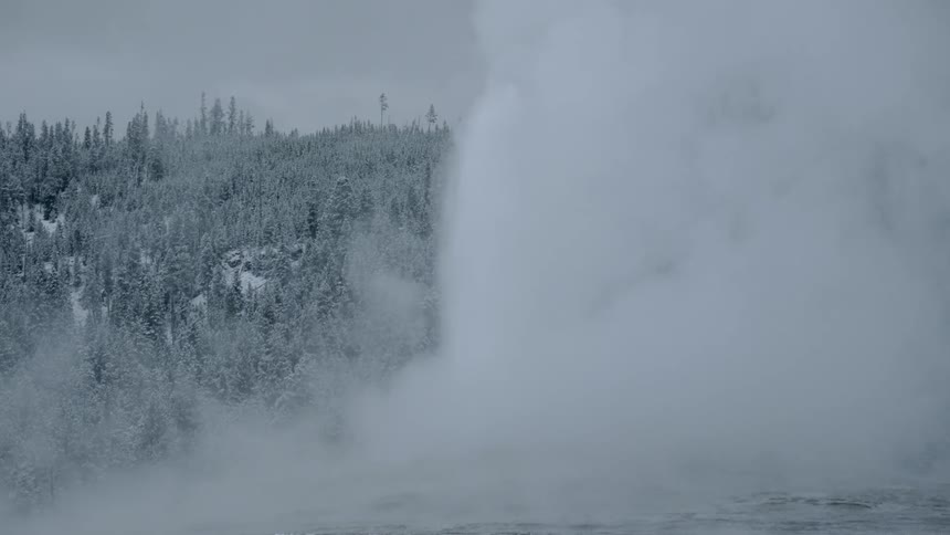 The water sprays up over the ice covered forest