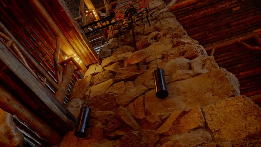 A pendulum swings from a clock mounted to a stone face in a lodge