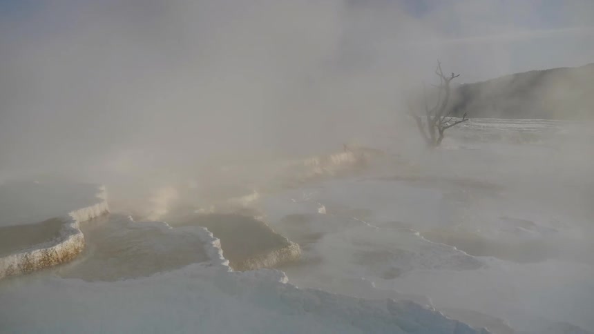Steam rises over the terrain from hot springs on a winter day