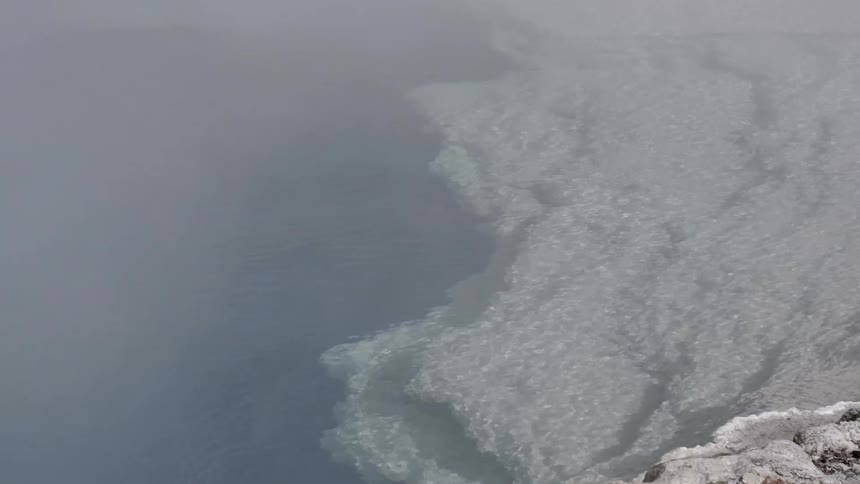 A hot spring with water rippling and steam coming off of it