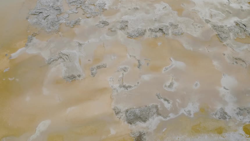 Birds eye view of a sandy beach with water and foam
