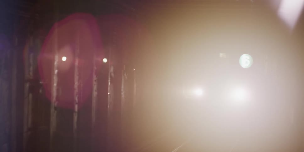 A subway train with people on board travels along the track at night