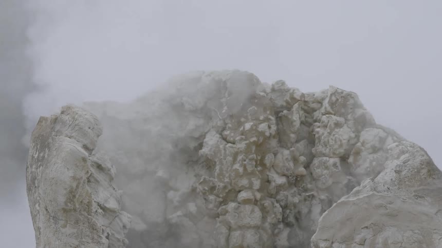 A calcified rock engulfed in steam emitted from the ground