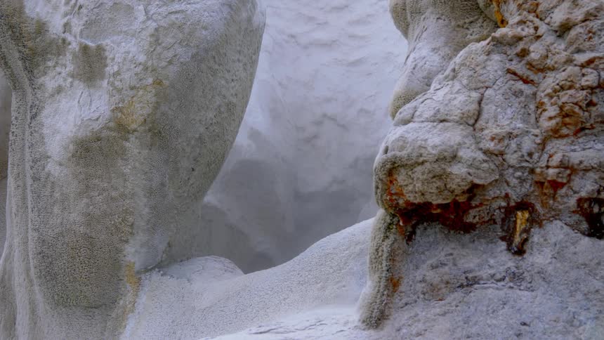 A snow mist drifts across frostcovered cliff walls