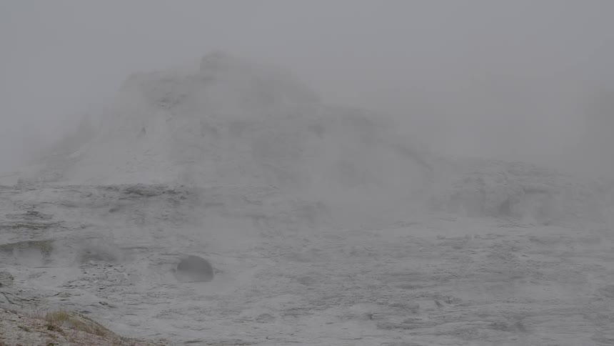 Fog covers a mountain peak covered in snow