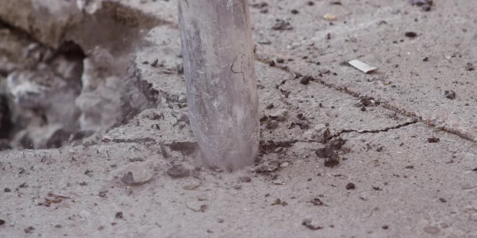 Slow motion shot of a jackhammer pounding through cement