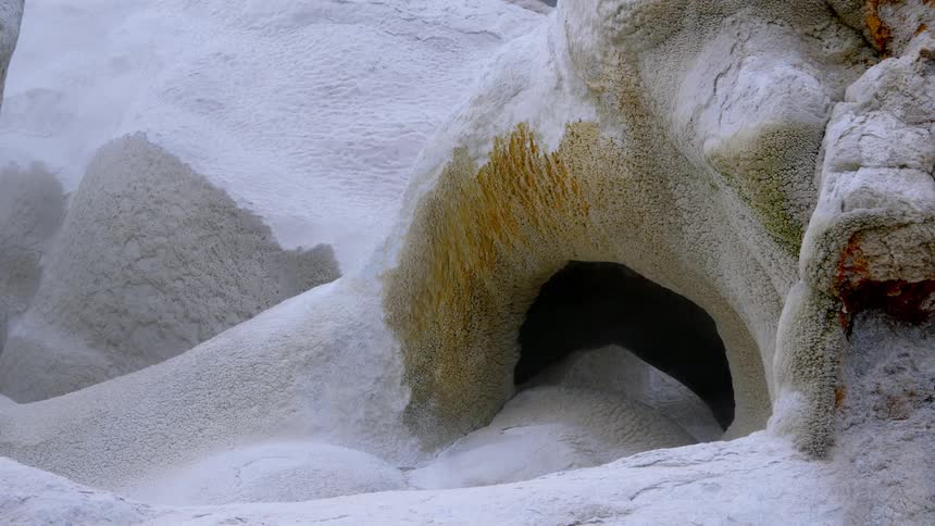 Snow blows across the front of a snow covered cave