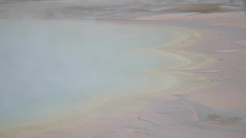 Steam rises from the aqua blue water of a hot spring