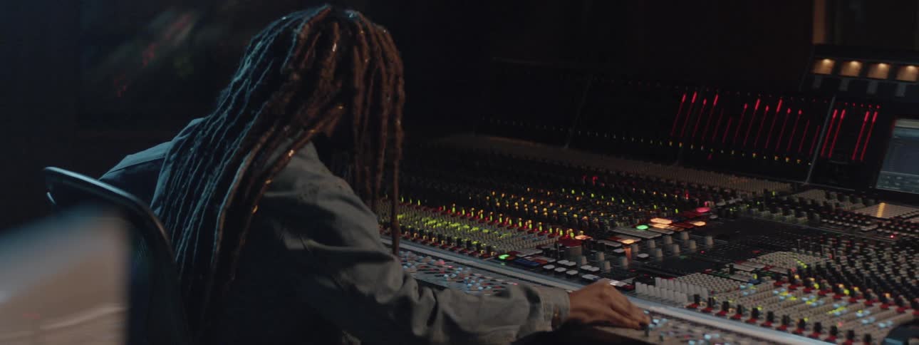 A person bounces to music while working a sound board