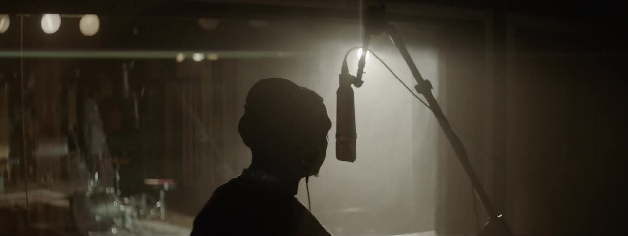 A young black man sings in to a microphone