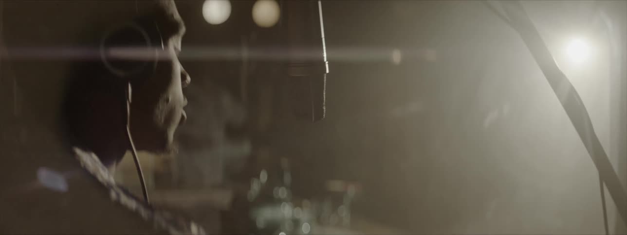 A man is wearing headphones as he sings into a microphone