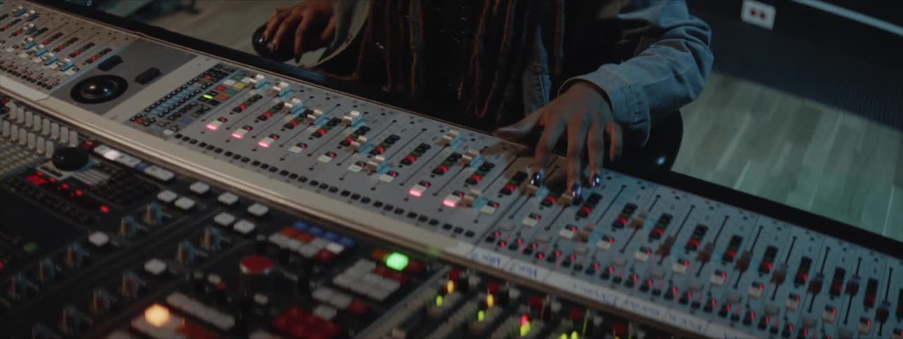 A person with dreadlocks using a sound mixer in a studio