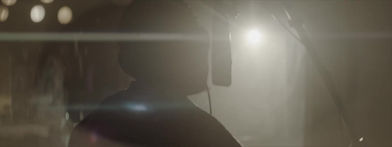 A young man recording a vocal track into a condenser microphone in a studio